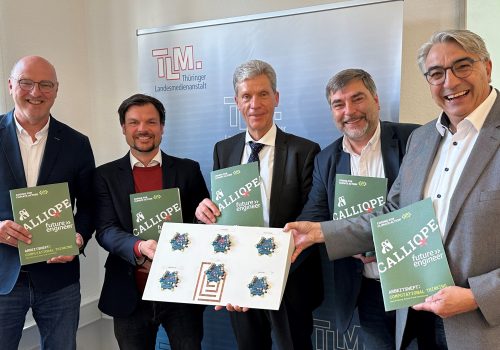 Fünf Herren stehen lächend vor einem TLM-Banner mit Calliope Projektmappen in den Händen