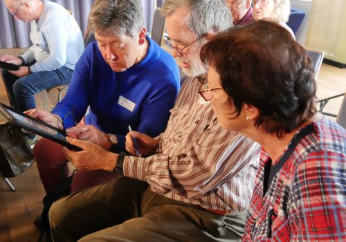 Drei Seniorinnen und Senioren schauen gemeinsam in ein Tablet
