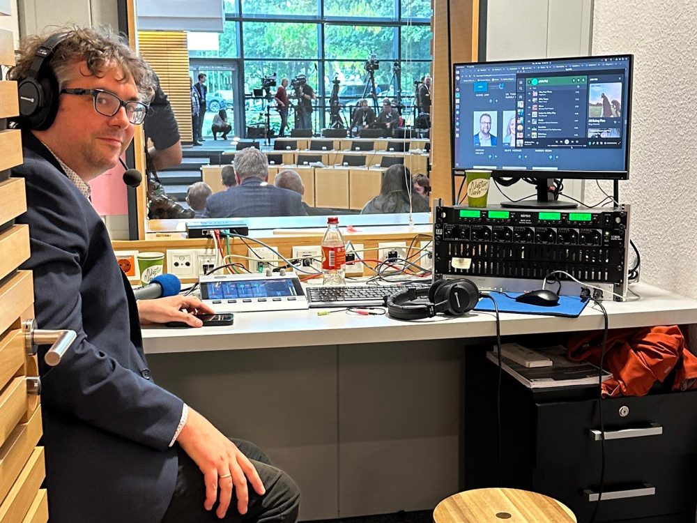 Ein Mann schaut aus einem kleinen Rundfunkstudio heraus.