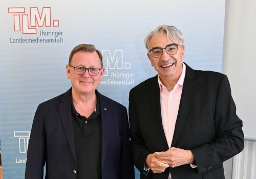 Zwei Männer stehen nebeneinander und lächeln in die Kamera.