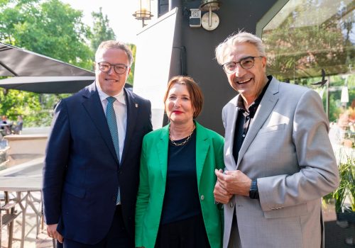 Eine Frau rechts und links ein Mann stehen nebeneinander und lächeln in die Kamera