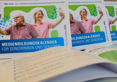 Cover des Medienbildungskalenders mit einem Mann und einer Frau, die ihr Handy hochhalten und ein Selfie machen