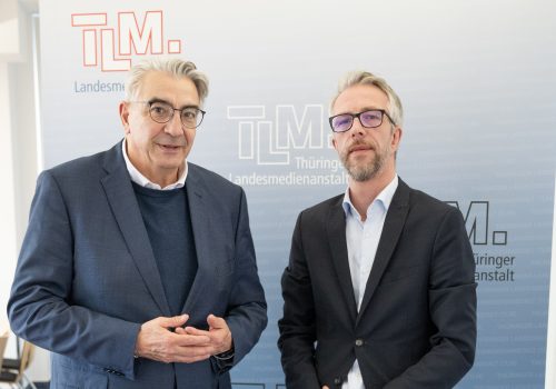 Zwei Männer stehen nebeneinander und schauen in die Kamera.