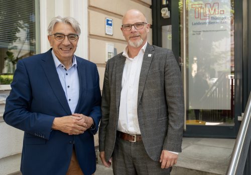 Zwei Männer stehen nebeneinander und lächeln in die Kamera