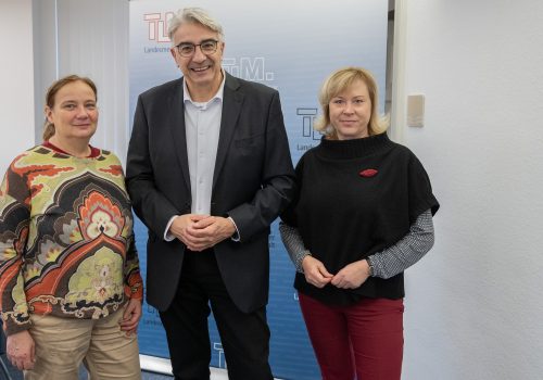 Zwei Frauen und ein Mann stehen nebeneinander und lächeln in die Kamera