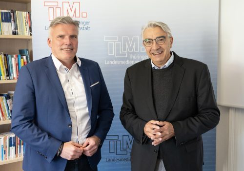 Zwei Männer stehen nebeneinander und lächeln in die Kamera