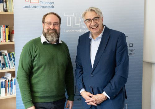 Zwei Männer stehen nebeneinander und lächeln in die Kamera.