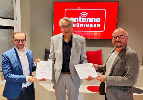 Drei Männer stehen vor dem Logo der Antenne Thüringen