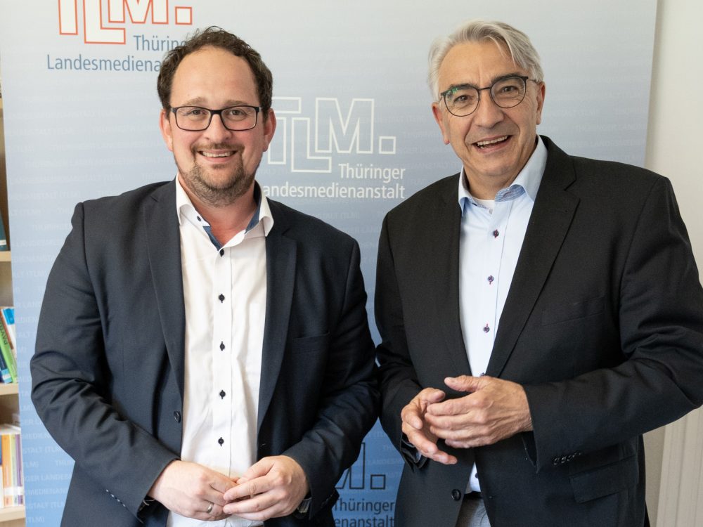 Zwei Männer stehen nebeneinander und lächeln in die Kamera