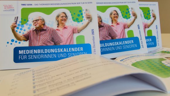 Cover des Medienbildungskalenders mit einem Mann und einer Frau, die ihr Handy hochhalten und ein Selfie machen
