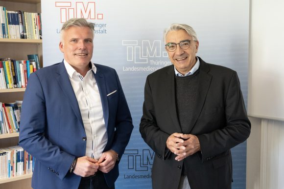 Zwei Männer stehen nebeneinander und lächeln in die Kamera