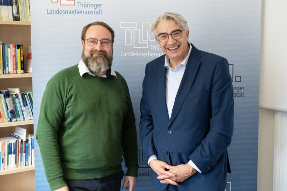 Zwei Männer stehen nebeneinander und lächeln in die Kamera.