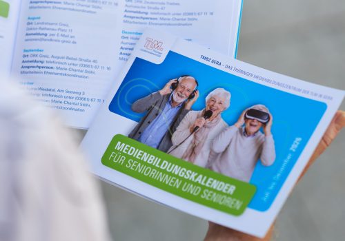 Coverfoto mit drei älteren Personen auf aufgeklappter Broschüre