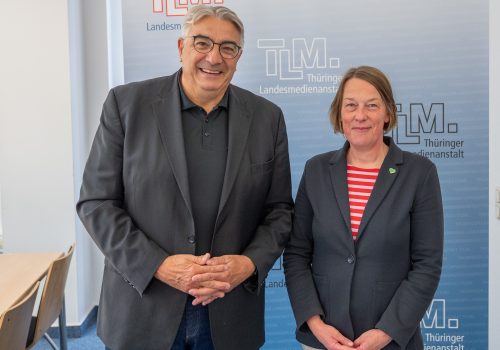 Ein Mann und eine Frau stehen nebeneinander und lächeln in die Kamera