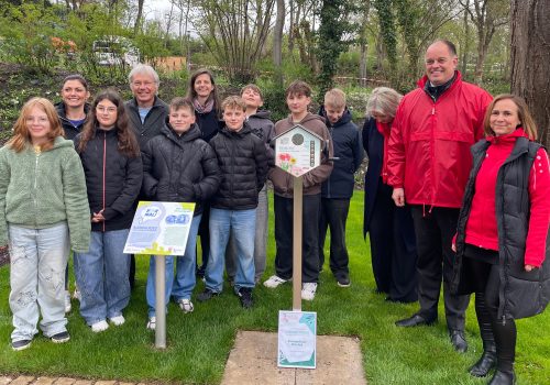 Kinder und Erwachsene stehen in einer Zweierreihe hinter der Hörstation