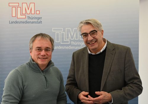 Zwei Männer stehen nebeneinander und lächeln in die Kamera