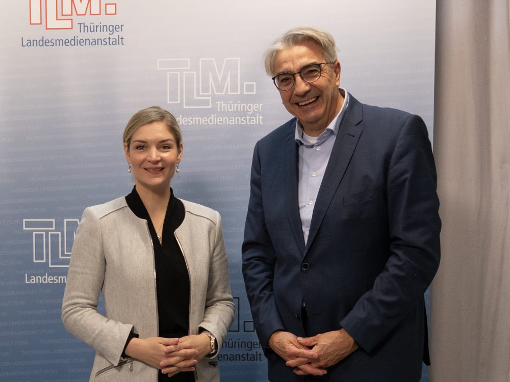 Eine Frau und ein Mann stehen nebeneinander und lächeln in die Kamera.