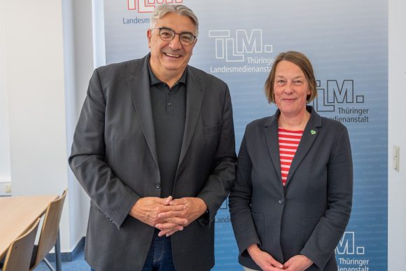 Ein Mann und eine Frau stehen nebeneinander und lächeln in die Kamera