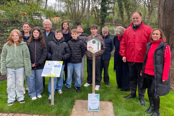 Kinder und Erwachsene stehen in einer Zweierreihe hinter der Hörstation