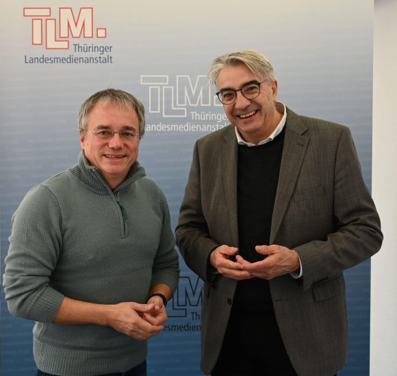 Zwei Männer stehen nebeneinander und lächeln in die Kamera