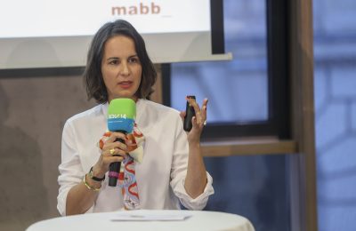 Eine Frau redet und hält ein Mikrofon in der Hand.