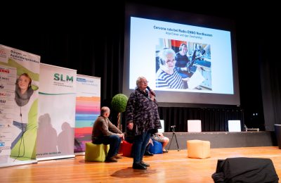 Eine Frau spricht auf der Bühne ins Mikrofon