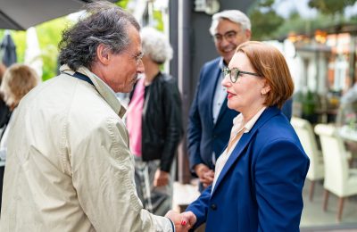 Eine Frau begrüßt eine Mann mit Handschlag