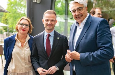 Eine Frau und zwei Männer lächeln in die Kamera