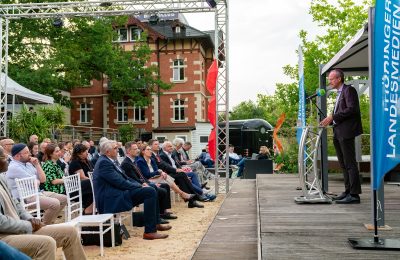 Ein Mann steht vor Publikum am Rednerpult
