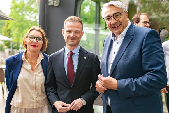 Eine Frau und zwei Männer lächeln in die Kamera