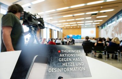 Veranstaltungssaal von hinten mit Kameramann und Einladung